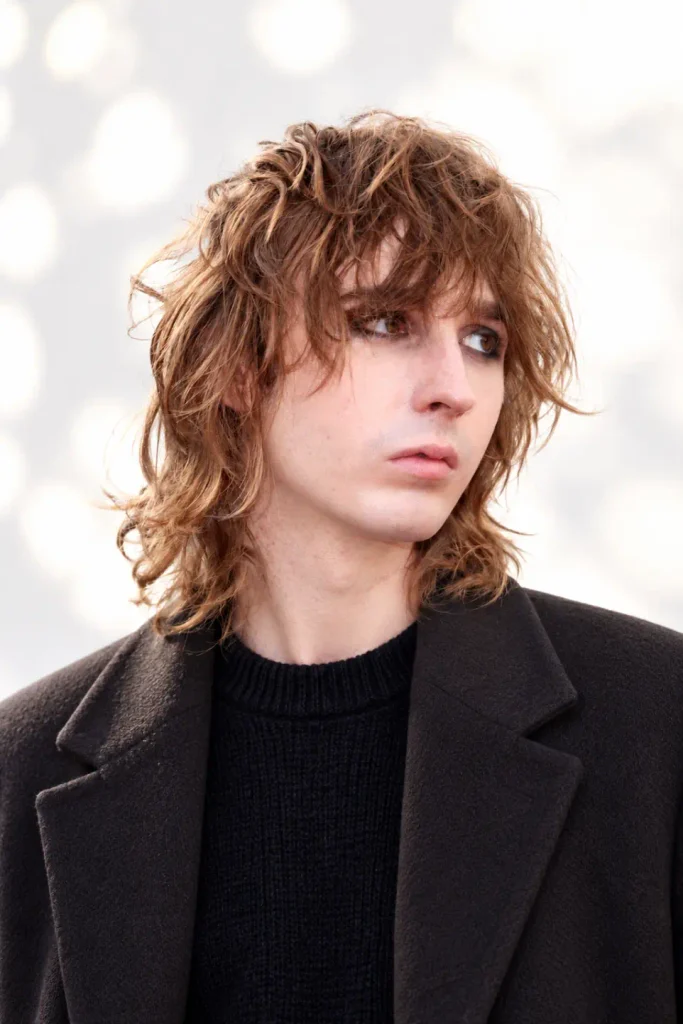 Men's 70s rock shag haircut with voluminous crown layers, feathered sides, and a full fringe